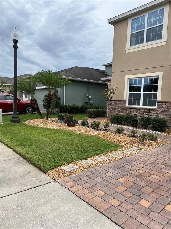 A two-story house exterior features a stone facade, a paver driveway, and a landscaped yard — 3318 STRATTON CIRCLE, KISSIMMEE, FL