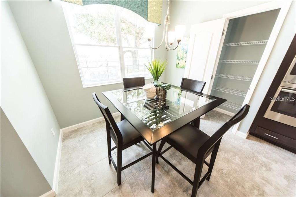 A dining area features a glass-topped table, four dark chairs, tile flooring, and a pantry — 3318 STRATTON CIRCLE, KISSIMMEE, FL