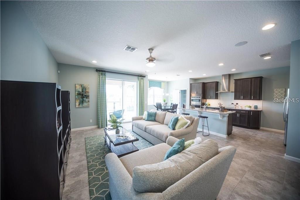 An open-concept living room and kitchen featuring tile floors, dark cabinetry, and a sliding glass door — 3318 STRATTON CIRCLE, KISSIMMEE, FL