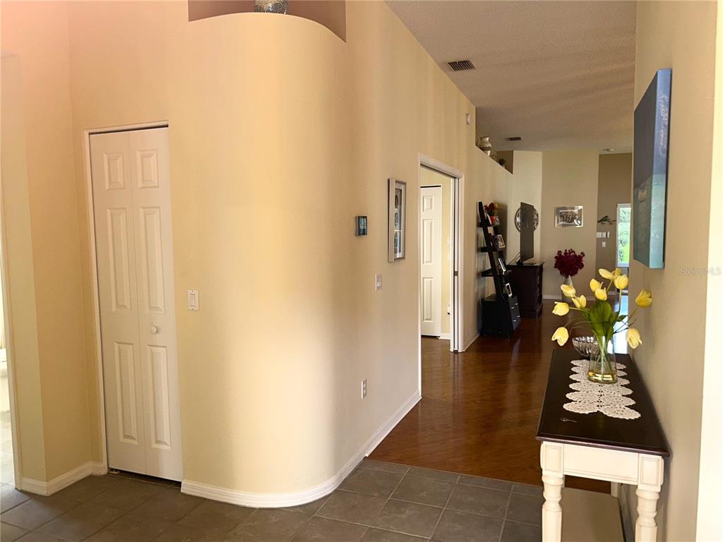A hallway with tiled flooring leads to a living area featuring hardwood floors and walls — 18505 GRAND CLUB DRIVE, HUDSON, FL