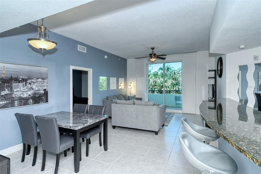 A living and dining area features a marble-topped table, gray sofa, and breakfast bar — 800 N TAMIAMI TRAIL UNIT 203, SARASOTA, FL
