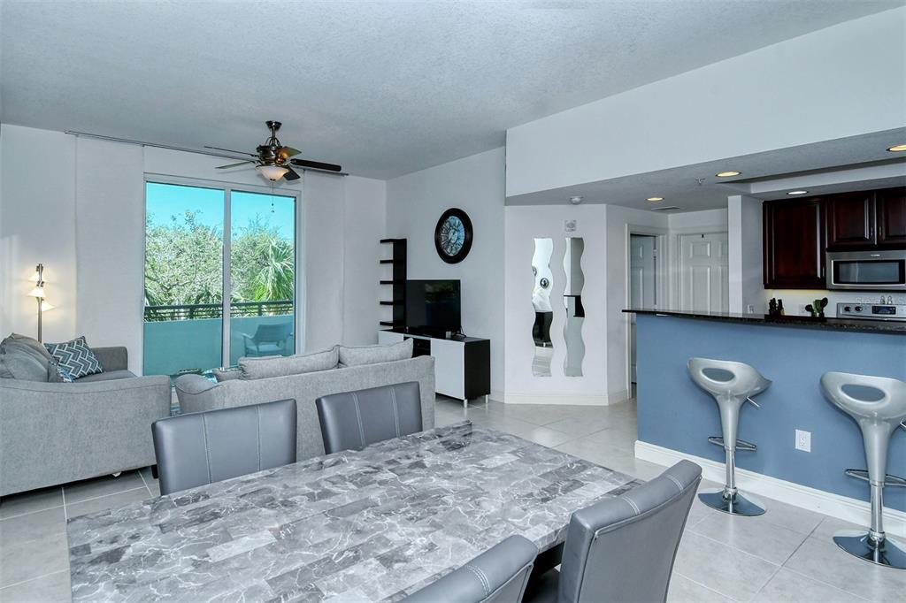 A living room and dining area feature a marble-topped table, gray sofas, and kitchen bar — 800 N TAMIAMI TRAIL UNIT 203, SARASOTA, FL