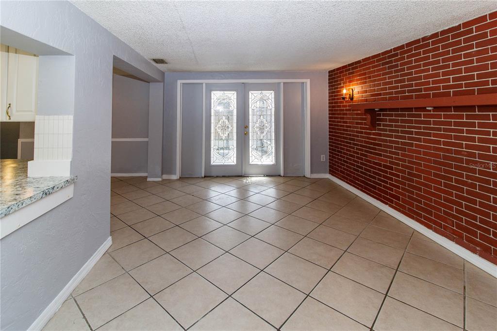 A dining room features a red brick wall, tile flooring, and double glass-paneled doors — 4150 NEWBURY DRIVE, NEW PORT RICHEY, FL