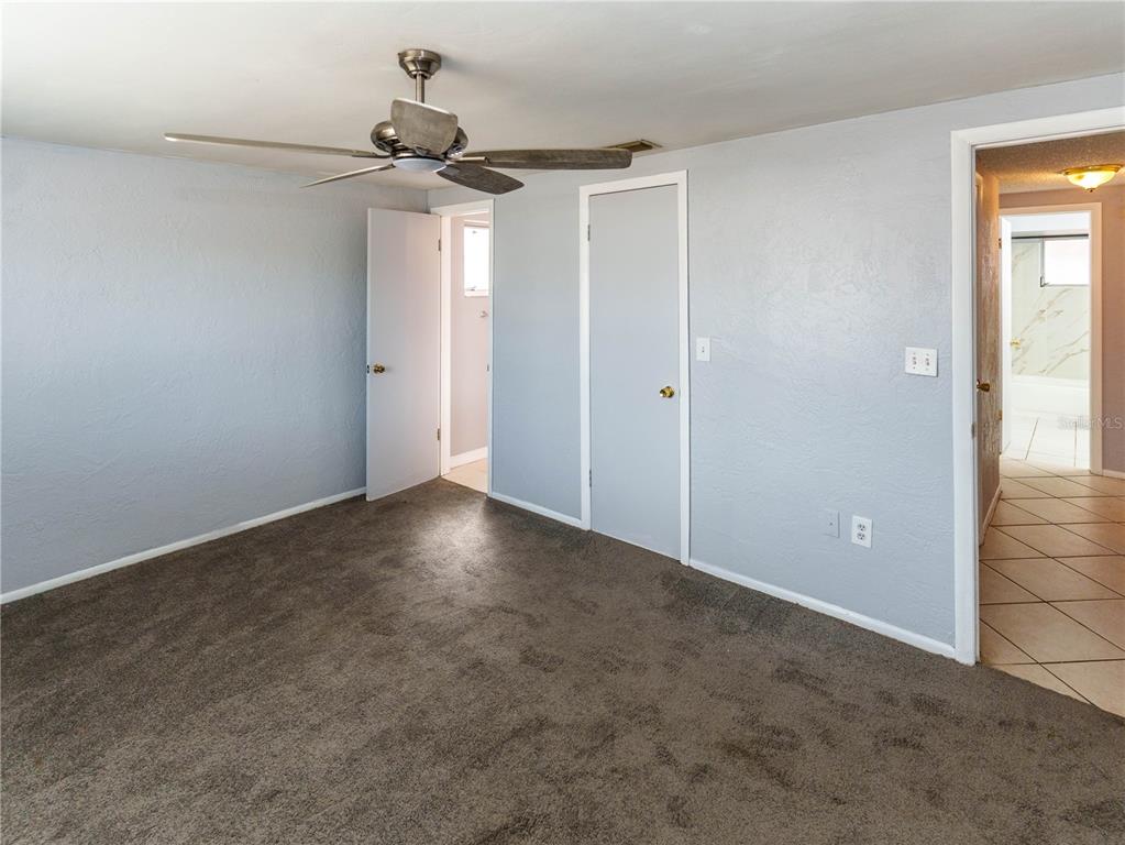 A bedroom with gray walls, brown carpet, a ceiling fan, and two doorways — 4150 NEWBURY DRIVE, NEW PORT RICHEY, FL