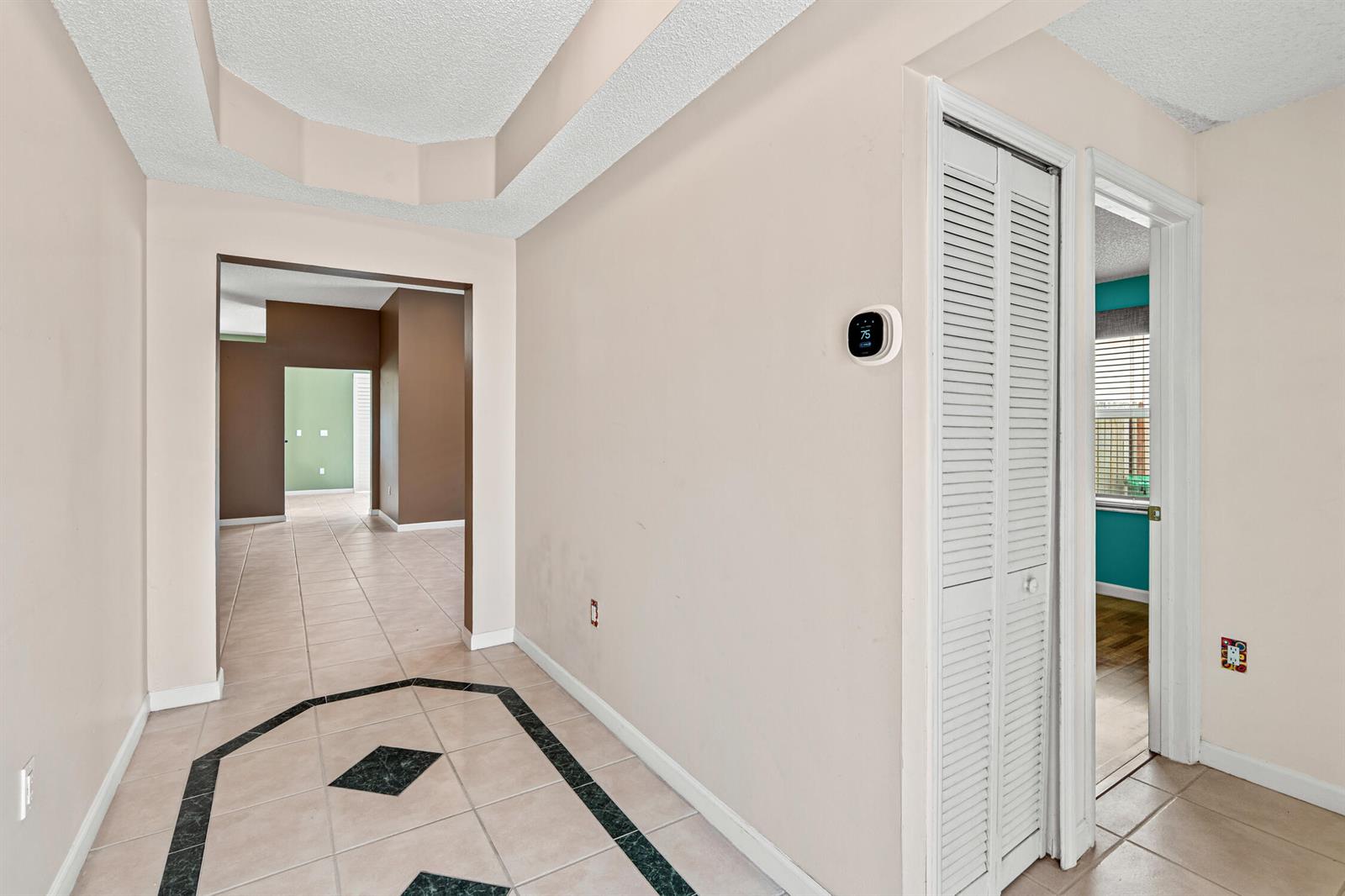 An empty room with beige tile flooring, white walls, and a hanging pendant light fixture — 376 E Royal Cove Circle, Davie FL 33325, DAVIE, FL