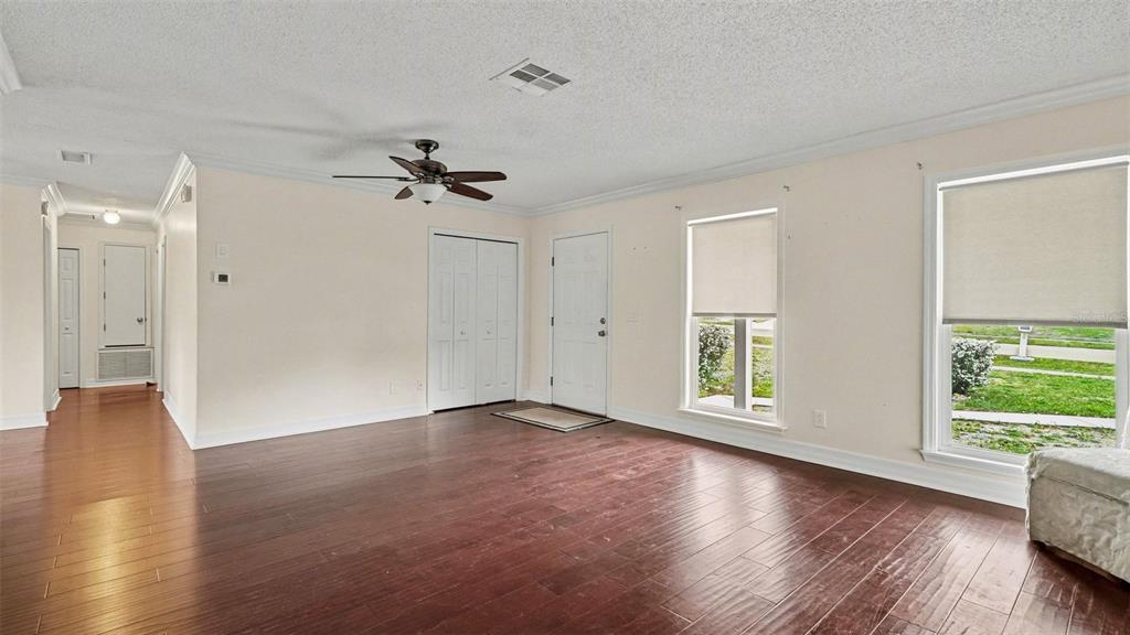 A living room features dark wood flooring, white walls, a ceiling fan, and two windows — 2434 W GARDENIA DRIVE, CITRUS SPRINGS, FL