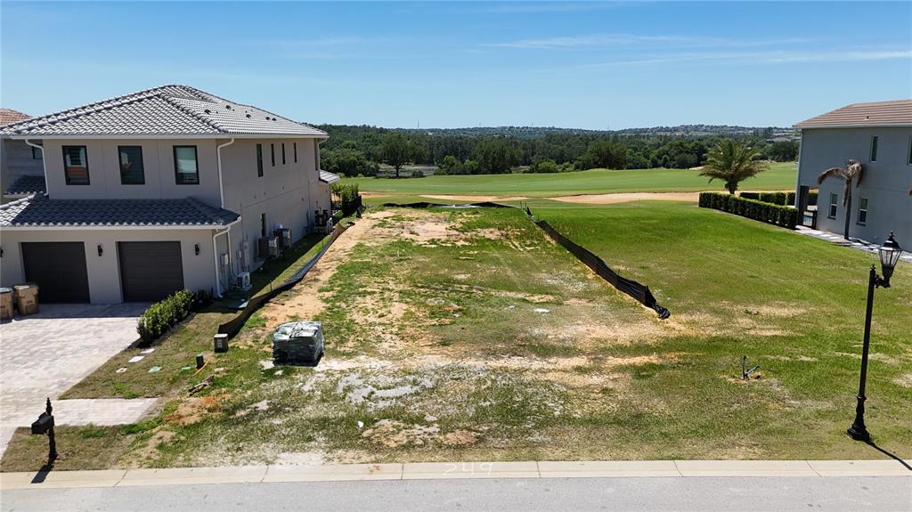 An empty residential lot sits between two houses with a view of a golf course — 15954 VETTA DRIVE, MONTVERDE, FL