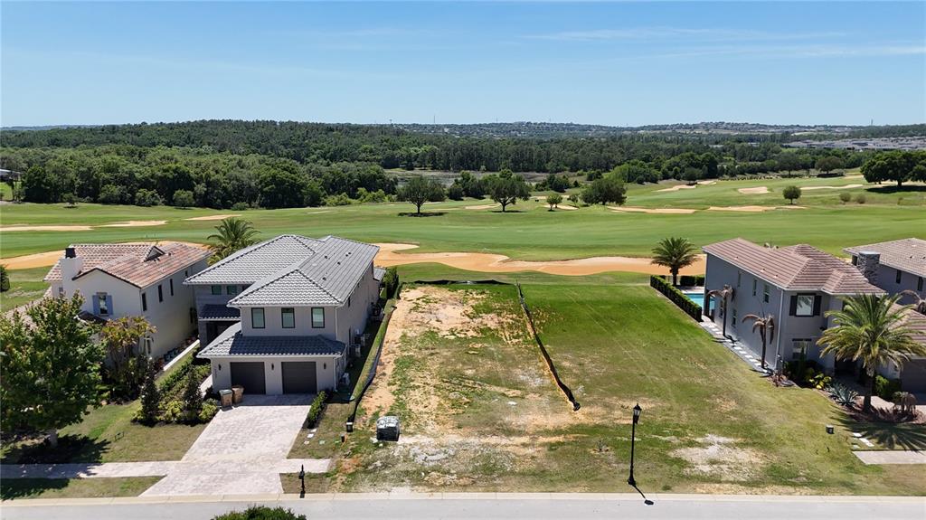 An aerial view shows a vacant residential lot situated between two houses overlooking a golf course — 15954 VETTA DRIVE, MONTVERDE, FL
