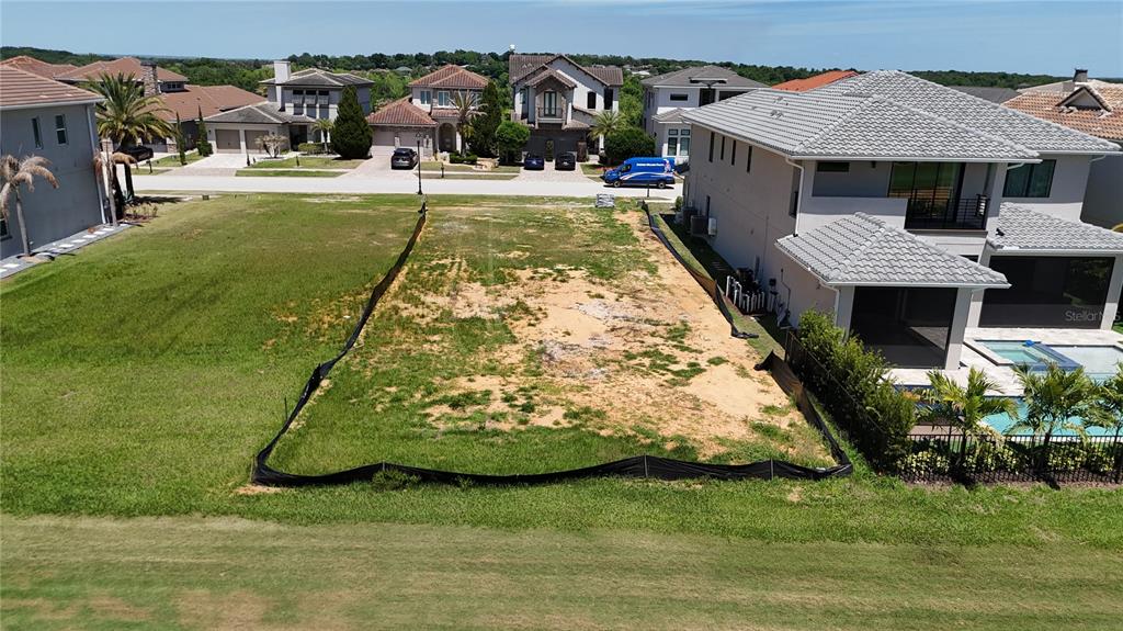 An aerial view shows a vacant residential lot enclosed by silt fencing between two houses — 15954 VETTA DRIVE, MONTVERDE, FL