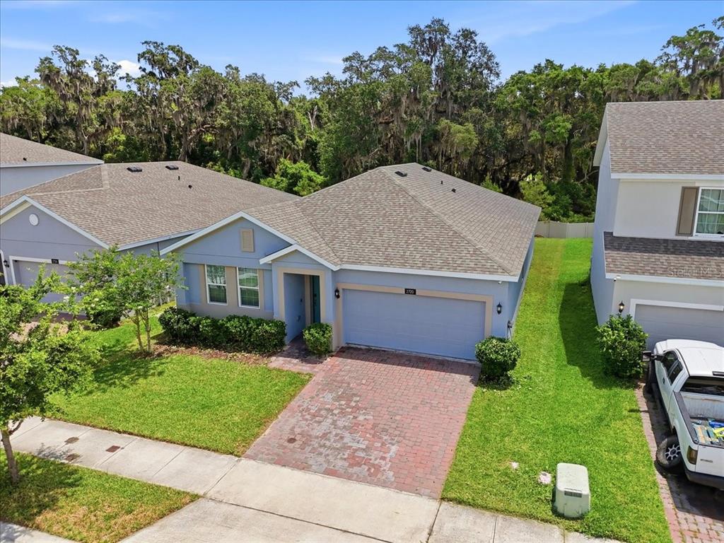 An aerial view of a blue single-story house with a brick driveway and shingled roof — 2720 NOTTEL DRIVE, ST CLOUD, FL
