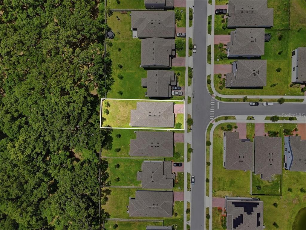 This aerial view shows a single-family home with a fenced backyard bordering a wooded area — 2720 NOTTEL DRIVE, ST CLOUD, FL