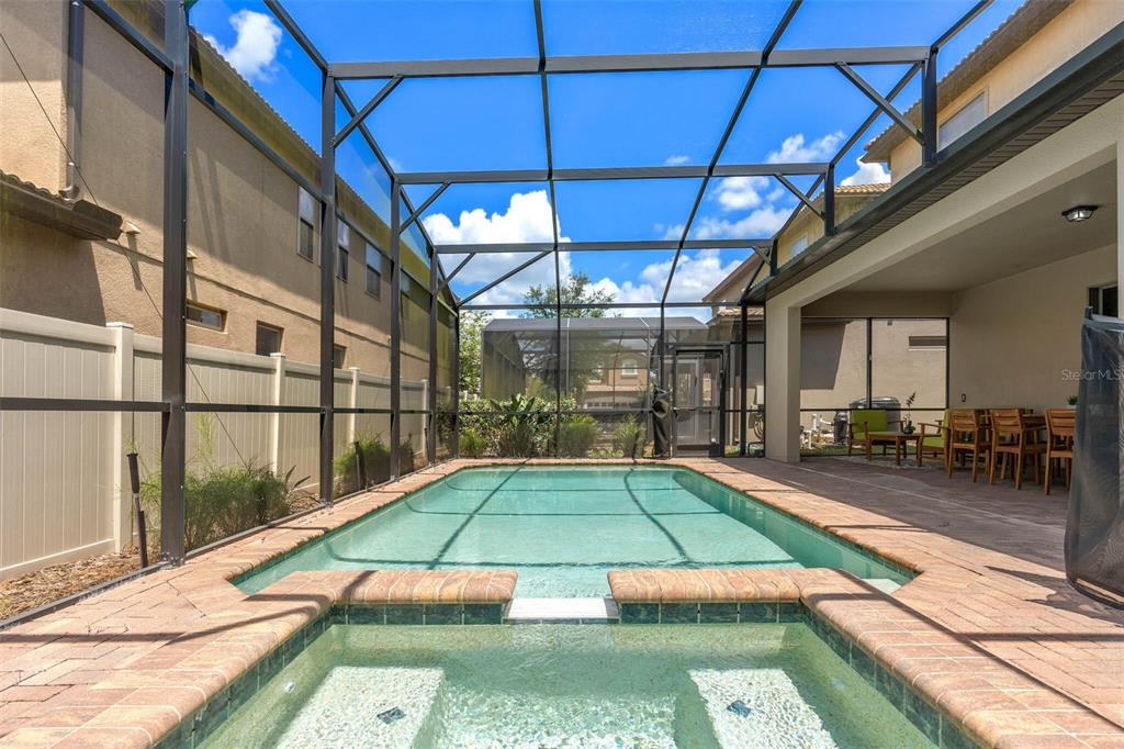 A screened-in patio features a swimming pool and attached spa with brick paver decking — 1940 NICE COURT, KISSIMMEE, FL