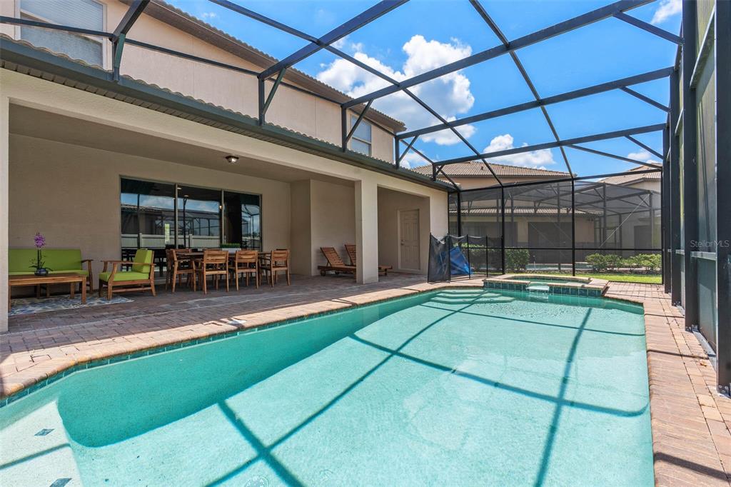 A screened-in patio features a swimming pool, hot tub, and outdoor dining furniture — 1940 NICE COURT, KISSIMMEE, FL