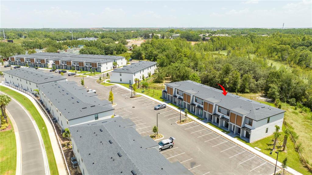 An aerial view shows several modern townhome buildings with parking lots and surrounding green space — 3245 TRANQUIL TRAIL, KISSIMMEE, FL