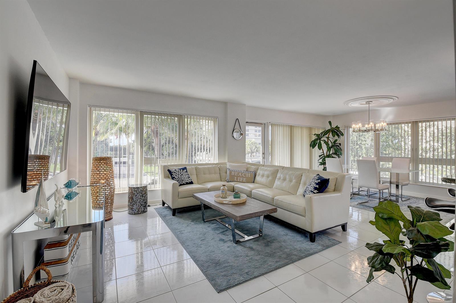 A bright living and dining area features white tile floors, a sectional sofa, and floor-to-ceiling windows — 2066 N Ocean Boulevard, Boca Raton FL 33431, BOCA RATON, FL