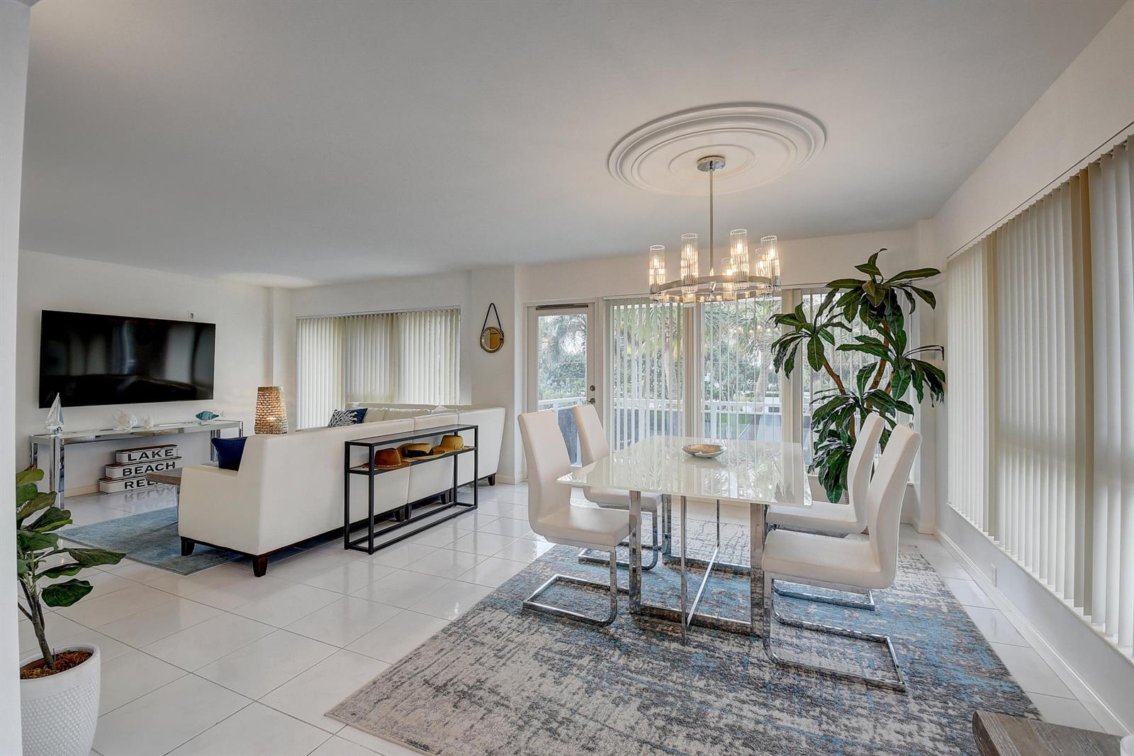 A bright open-concept living and dining area with white tile floors and modern furniture — 2066 N Ocean Boulevard, Boca Raton FL 33431, BOCA RATON, FL
