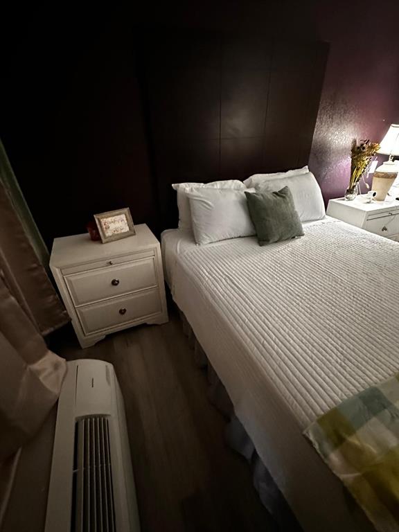 A bedroom features a bed with a tall dark headboard, white nightstands, and an air conditioner — 2050 E IRLO BRONSON MEMORIAL HIGHWAY UNIT 108, KISSIMMEE, FL