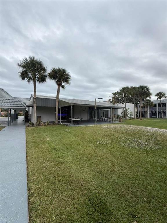 A grassy lawn leads to a covered patio area with palm trees under a cloudy sky — 2050 E IRLO BRONSON MEMORIAL HIGHWAY UNIT 108, KISSIMMEE, FL