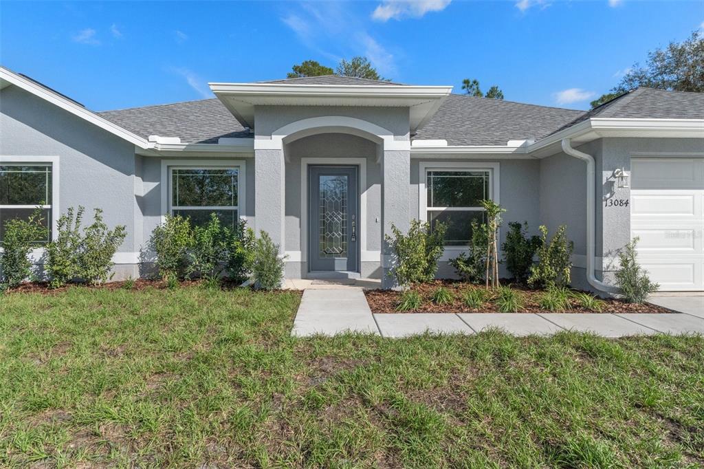 An open dining area with wood-look tile flooring, a chandelier, and an arched kitchen doorway — 17 HAWTHORNE COURT, HOMOSASSA, FL
