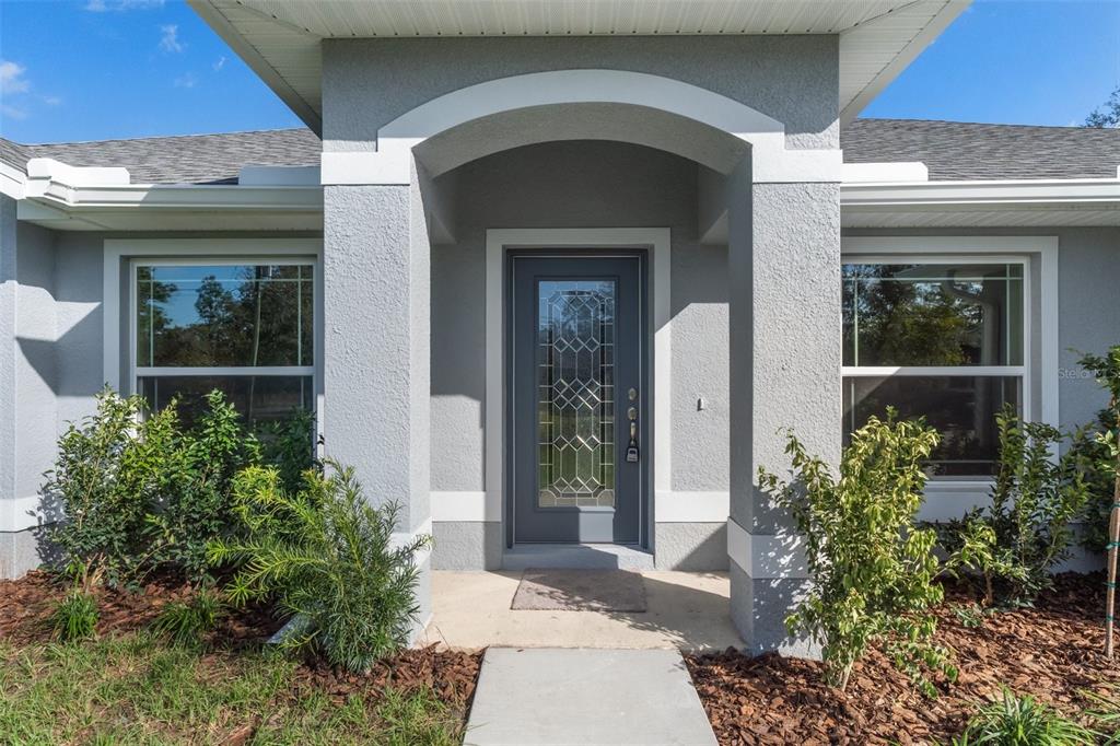 A kitchen features light wood cabinets, granite countertops, stainless steel appliances, and wood-look tile flooring — 17 HAWTHORNE COURT, HOMOSASSA, FL