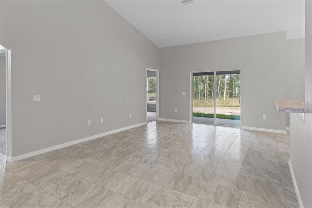 An open-concept living area features light wood-look tile flooring and a kitchen with wood cabinets — 17 HAWTHORNE COURT, HOMOSASSA, FL