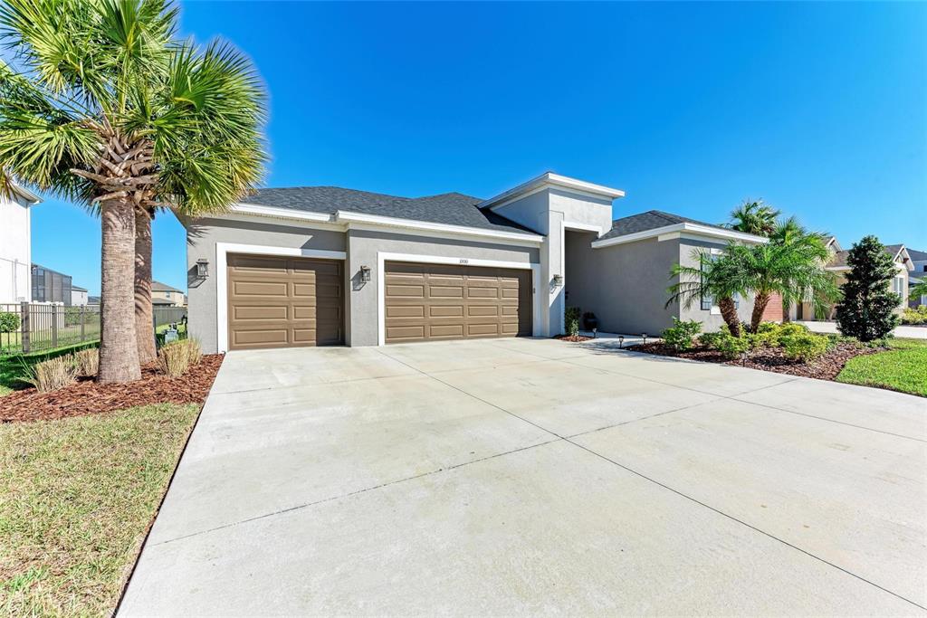 A single-story house with a three-car garage, palm trees, and a concrete driveway — 10010 BUCKMAN HALLS DRIVE, PALMETTO, FL