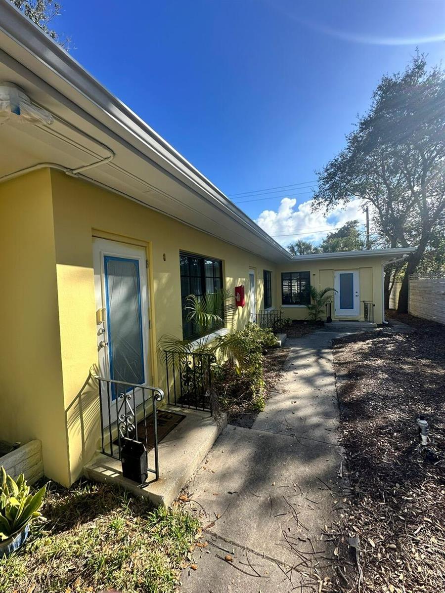 Exterior view of a yellow single-story apartment building with a concrete walkway and landscaping — 214 S Palmway, FL 33460, FL