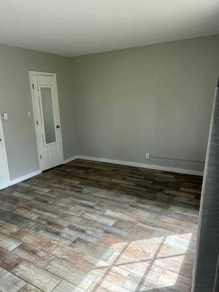 An empty room features gray walls, wood-look tile flooring, and a white door with glass — 214 S Palmway, FL 33460, FL