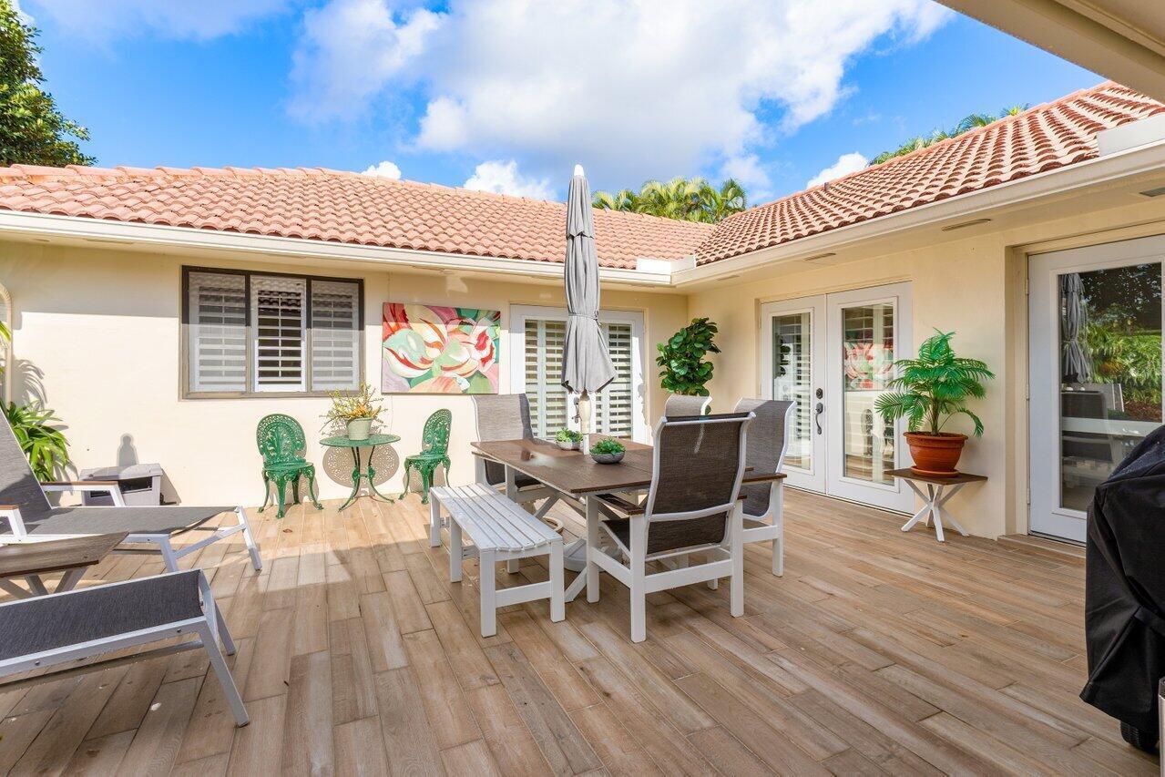 A patio with wood-look tile flooring, outdoor dining furniture, and lounge chairs under a roof — 4265 Shelldrake Lane, Boynton Beach FL 33436, BOYNTON BEACH, FL