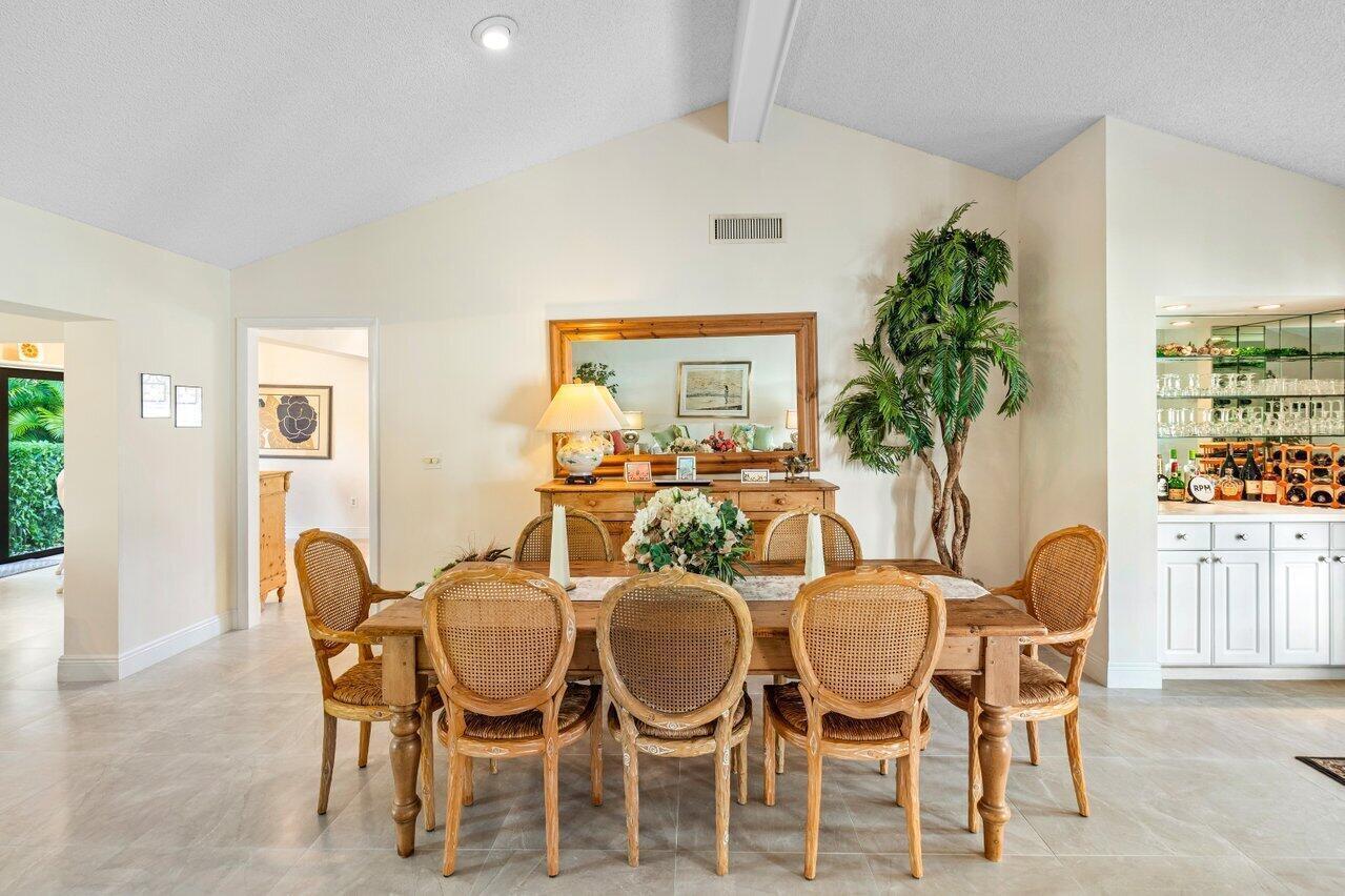 A dining room features a wooden table with six cane-back chairs and a wet bar — 4265 Shelldrake Lane, Boynton Beach FL 33436, BOYNTON BEACH, FL