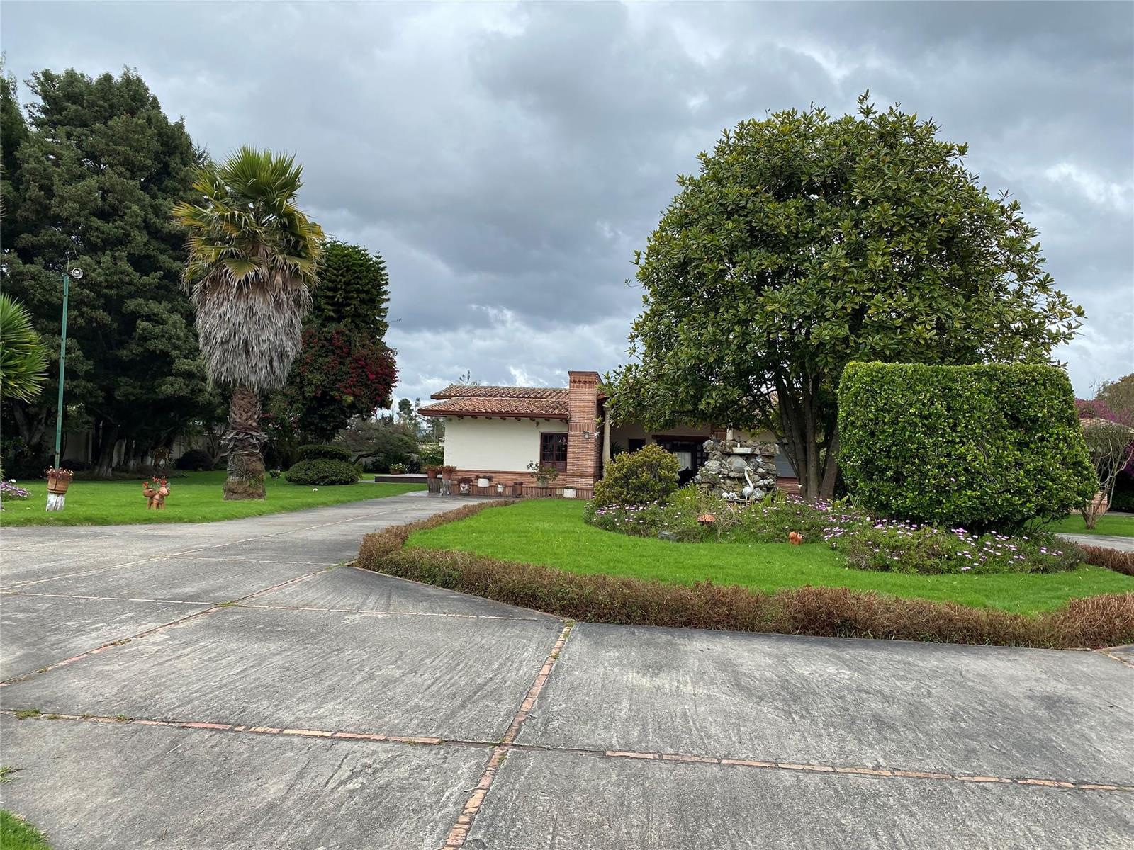 A single-story house with a tiled roof sits behind a large lawn and concrete driveway — NOT IN USA Not In Usa Guaymaral- Colombia, FL