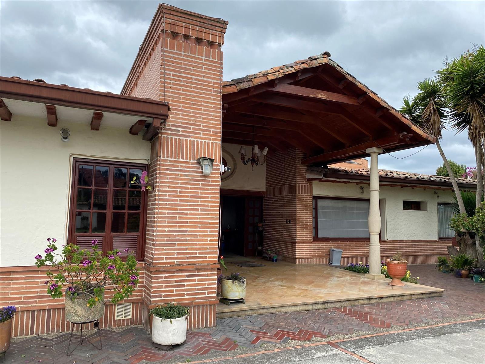 A brick and stucco house features a covered porch with a wooden roof and stone column — NOT IN USA Not In Usa Guaymaral- Colombia, FL