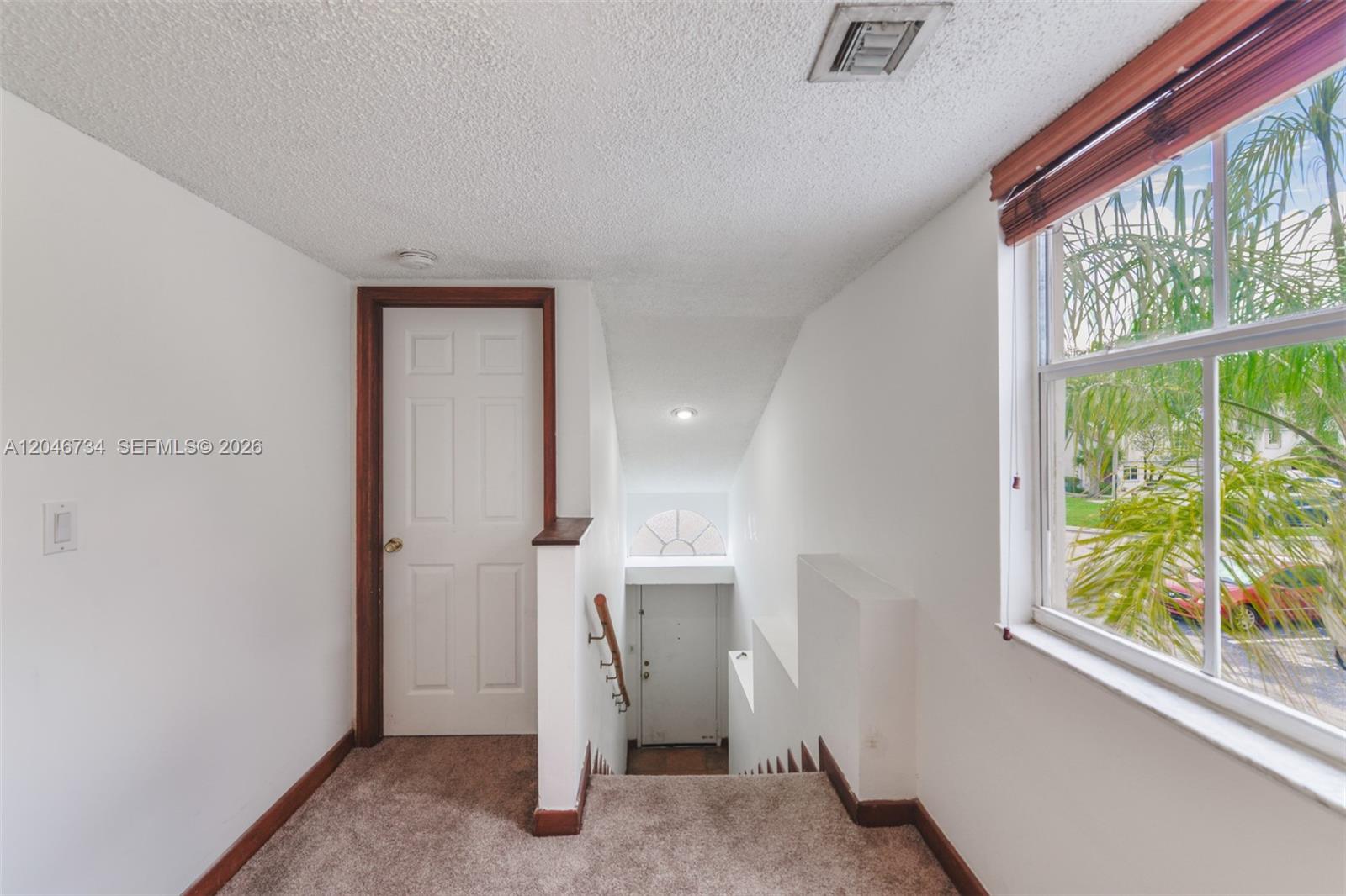 A carpeted landing features a white door, a staircase leading down, and a large window — 4990 NW 97th Pl # 314, Doral FL 33178, DORAL, FL