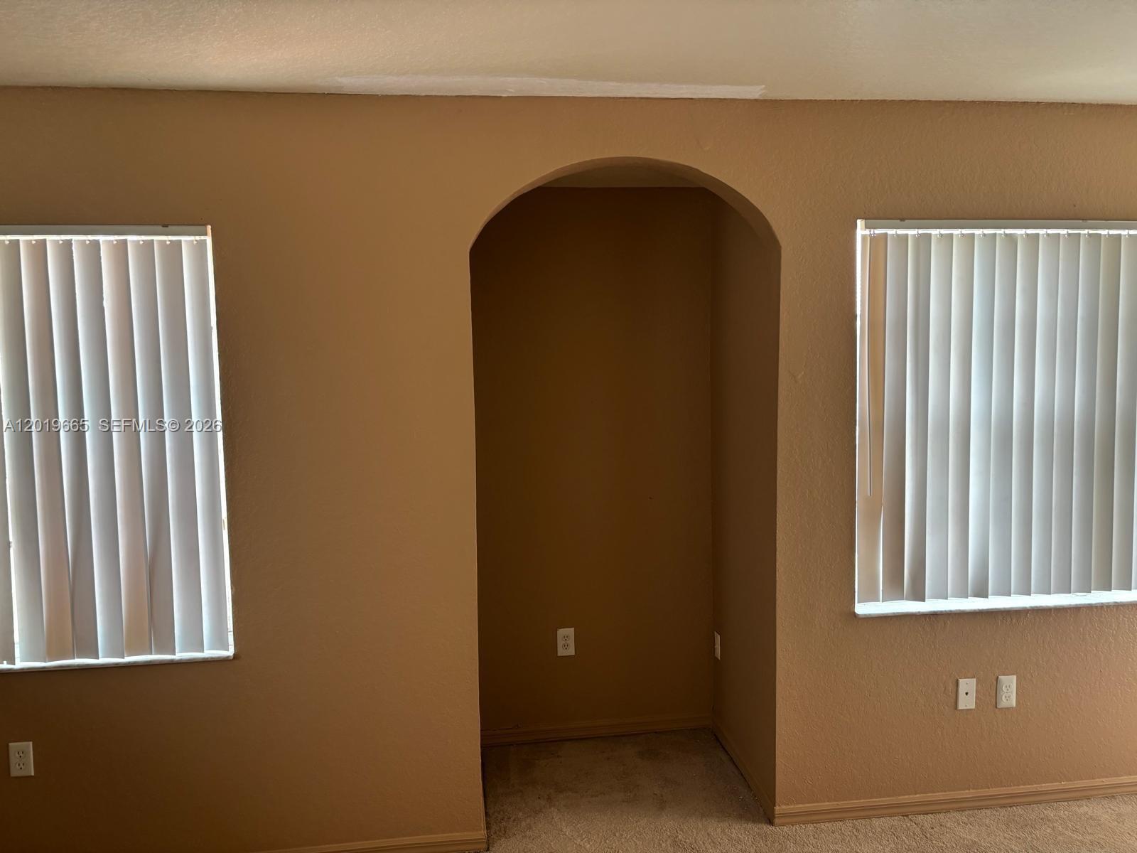 A room with tan walls, two windows with vertical blinds, and a central arched alcove — NORTH LAUDERDALE, FL