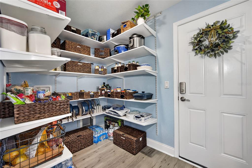 A walk-in pantry features white adjustable shelving, woven storage baskets, and light blue walls — 4101 POINCIANA DRIVE, INDIAN LAKE ESTATES, FL
