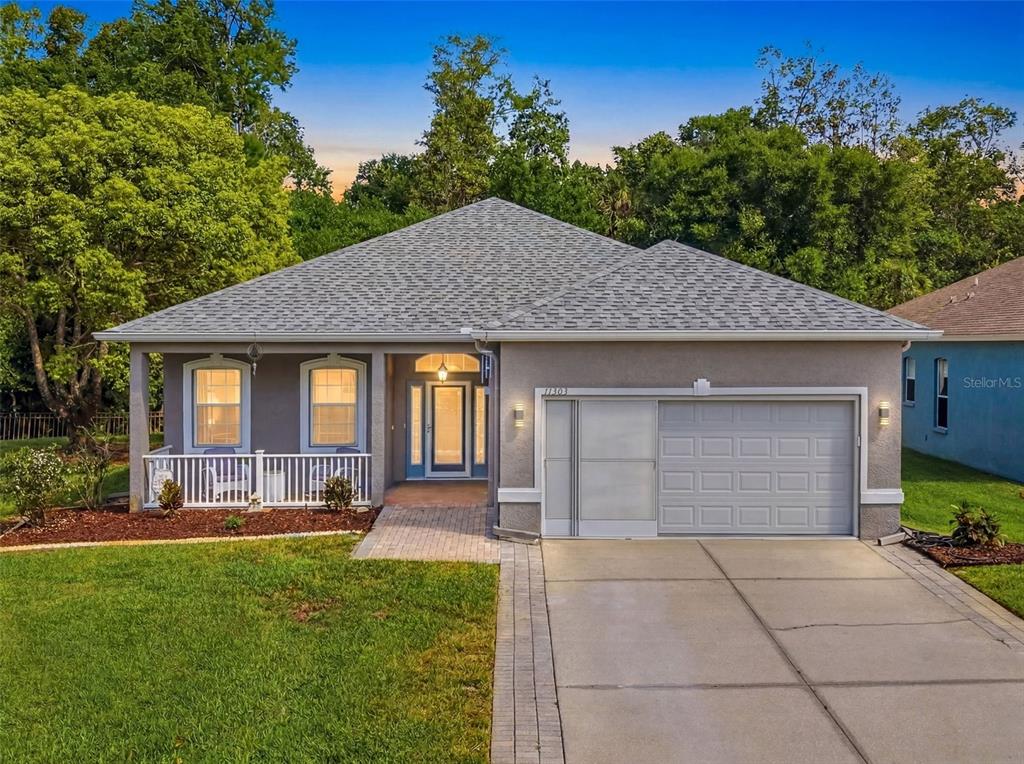 A single-story house with a gray stucco exterior, a front porch, and an attached garage — 11303 CLEAR OAK CIRCLE, NEW PORT RICHEY, FL