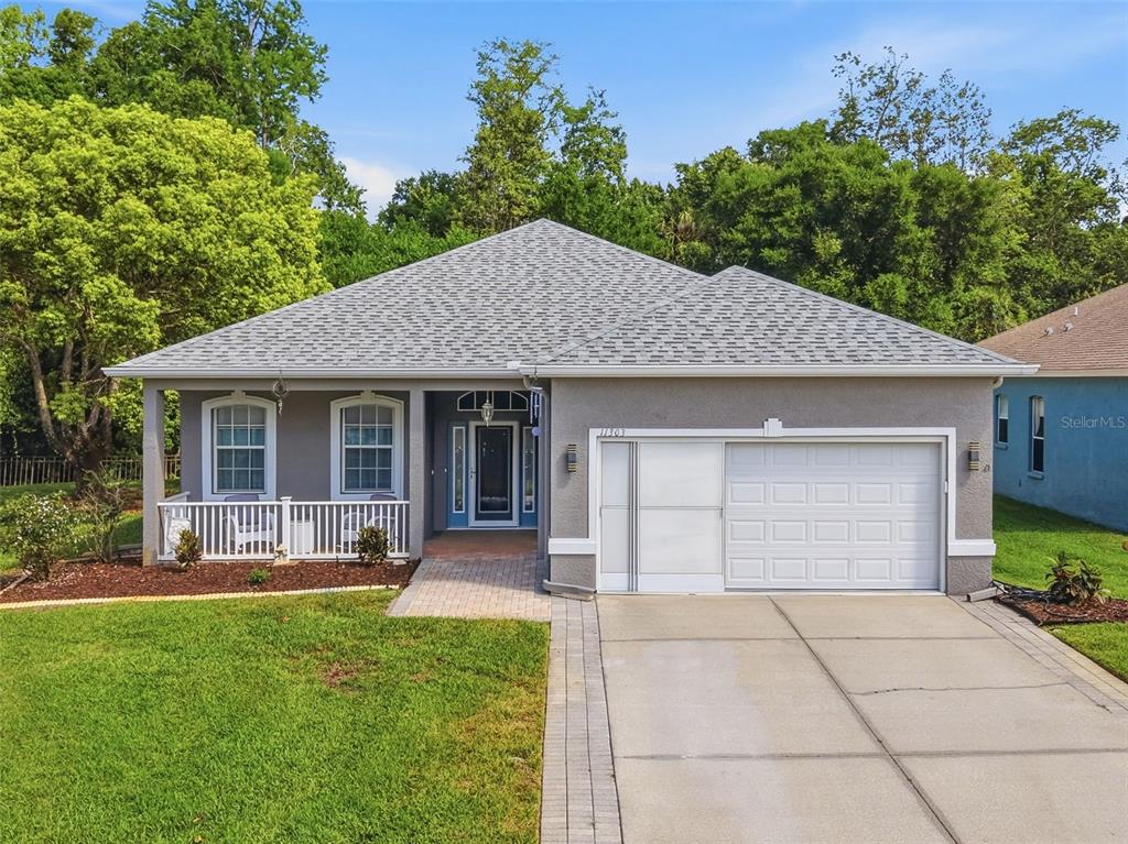 A gray single-story house features a front porch, a two-car garage, and a paved driveway — 11303 CLEAR OAK CIRCLE, NEW PORT RICHEY, FL