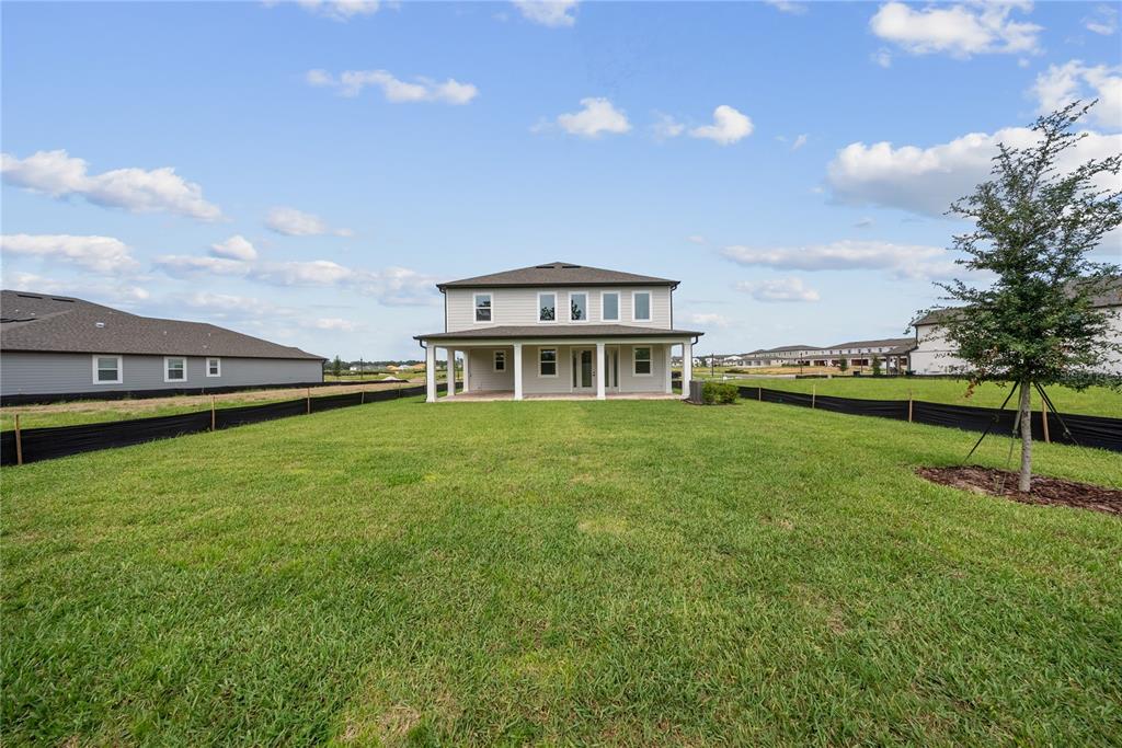 A two-story house with a covered patio sits in a large, grassy backyard — 12890 EUREKA LEMON DRIVE, WINTER GARDEN, FL