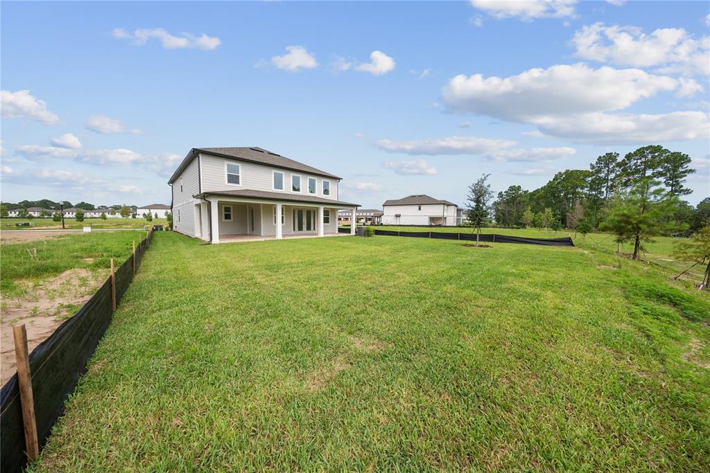 The exterior rear view of a two-story house features a covered patio and grassy yard — 12890 EUREKA LEMON DRIVE, WINTER GARDEN, FL