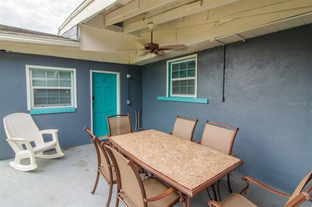 A covered patio features a dining table with chairs, a rocking chair, and blue walls — 1731 GRAYSON DRIVE UNIT 2, ORLANDO, FL