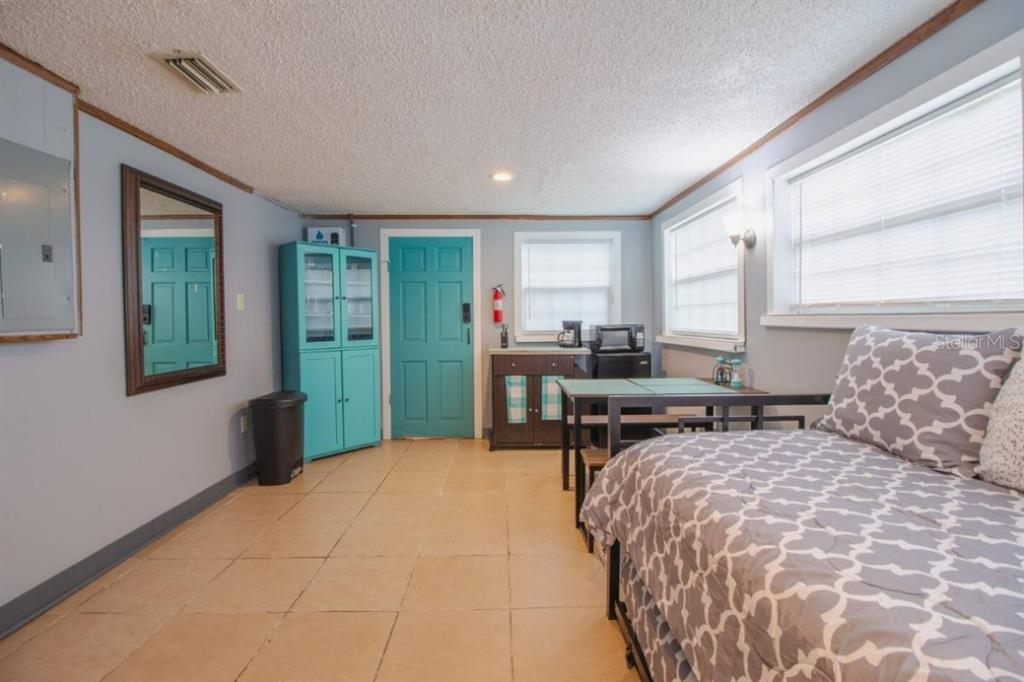 A bedroom with light blue walls, tile flooring, a teal door, and a twin bed — 1731 GRAYSON DRIVE UNIT 2, ORLANDO, FL