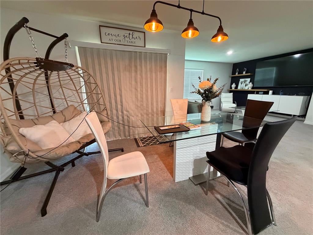 A dining room features a glass table, black chairs, a hanging chair, and pendant lighting — 17425 NW 173 ROAD, ALACHUA, FL