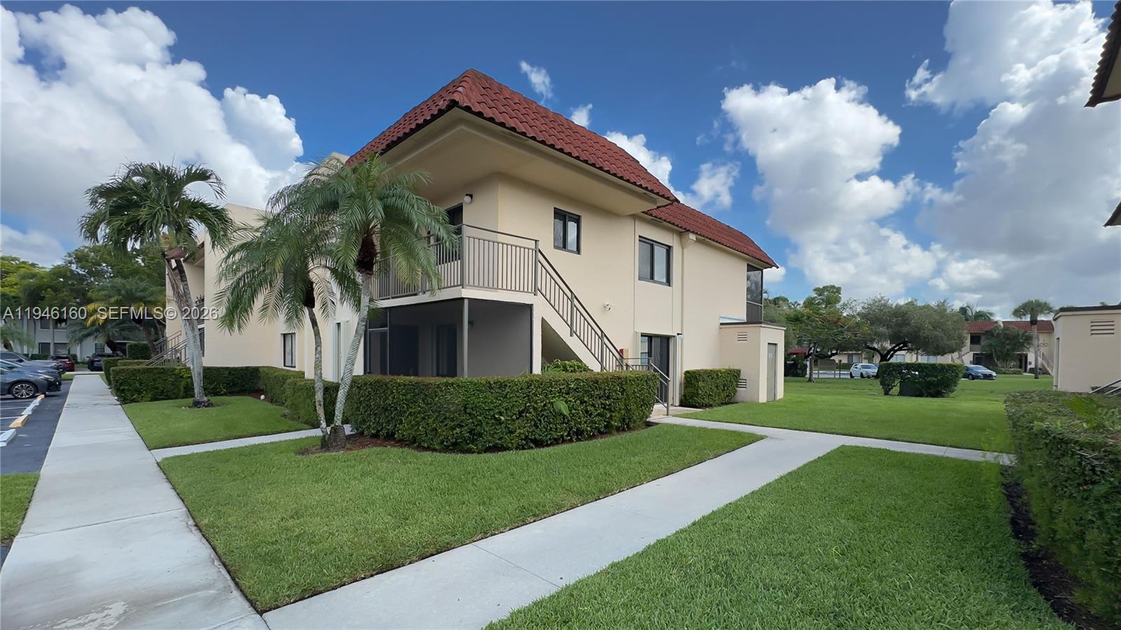 A two-story apartment building features a red tile roof, beige stucco walls, and exterior stairs — 16461 Blatt Blvd # 104, Weston FL 33326, WESTON, FL