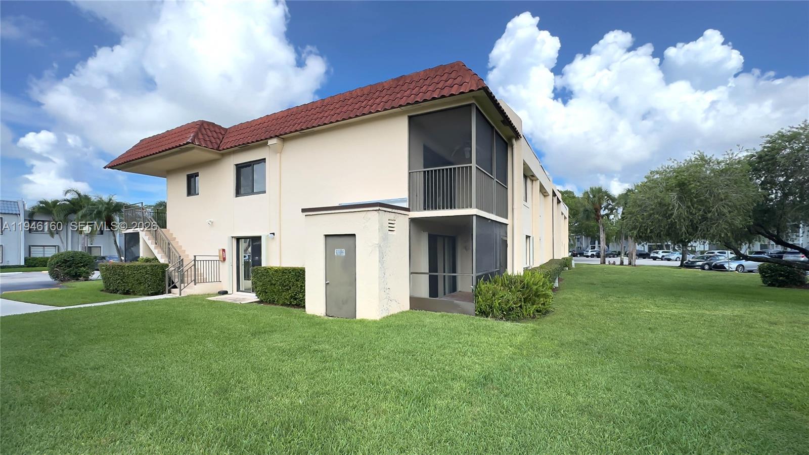 The exterior of a two-story apartment building features a red tile roof and screened balconies — 16461 Blatt Blvd # 104, Weston FL 33326, WESTON, FL