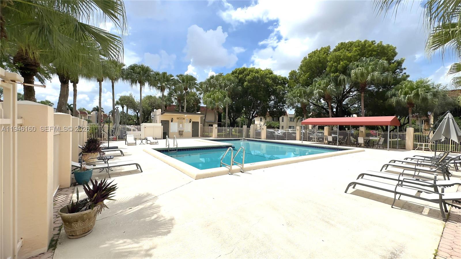 An outdoor swimming pool is surrounded by a concrete deck, lounge chairs, and palm trees — 16461 Blatt Blvd # 104, Weston FL 33326, WESTON, FL