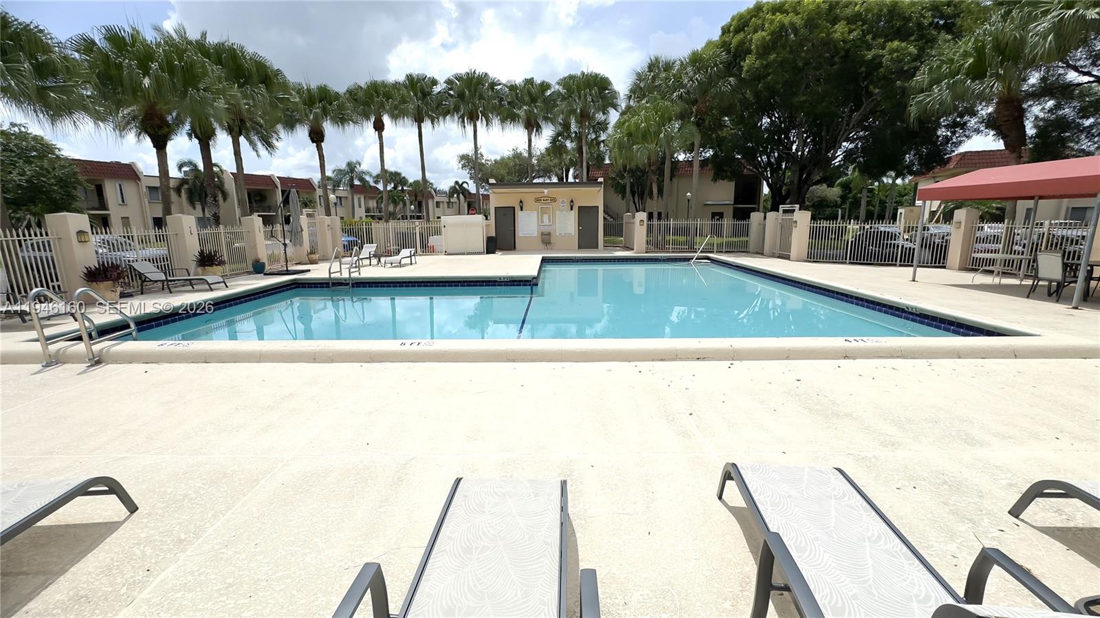 A rectangular swimming pool is surrounded by a concrete deck and palm trees — 16461 Blatt Blvd # 104, Weston FL 33326, WESTON, FL