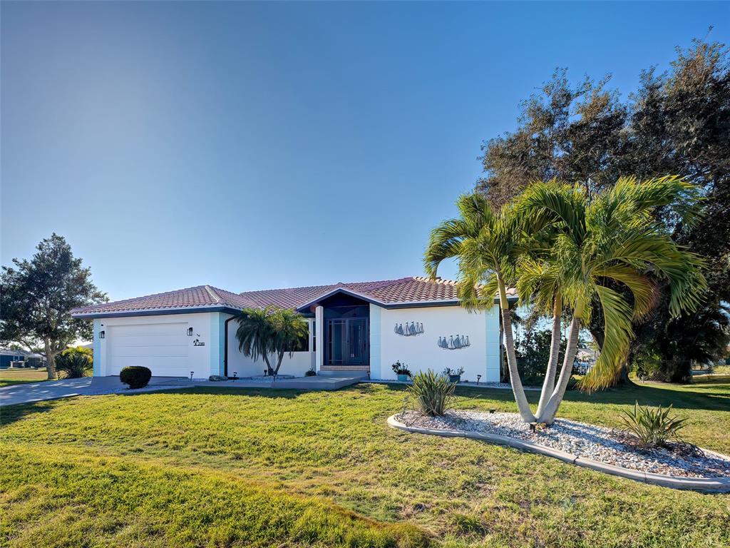 A single-story house with a white exterior, a tiled roof, and palm trees in the yard — 2301 VIA VENETO DRIVE, PUNTA GORDA, FL