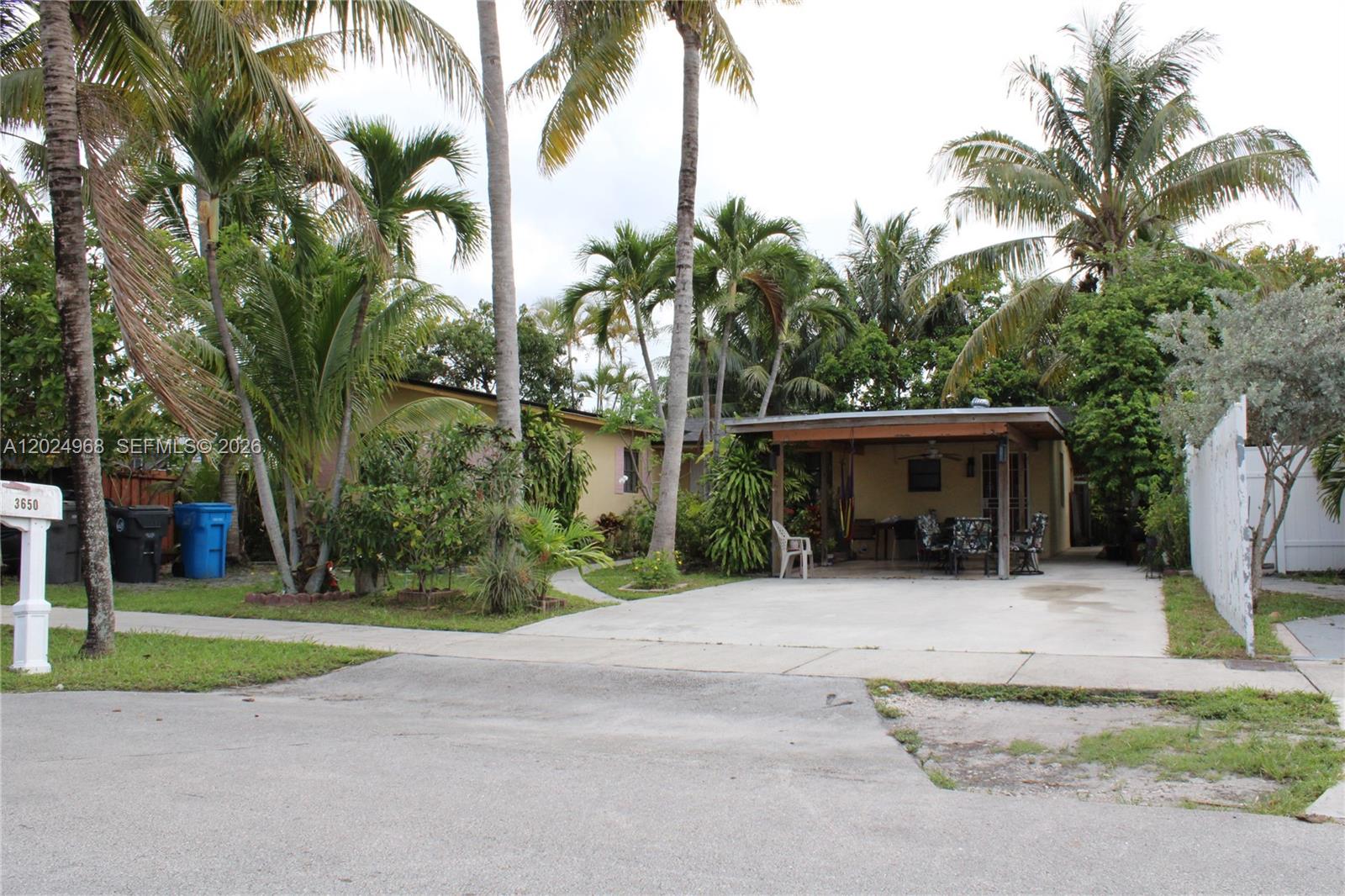 A single-story house features a concrete driveway, a covered patio, and several tall palm trees — 3650 SW 39th Ave, West Park FL 33023, WEST PARK, FL