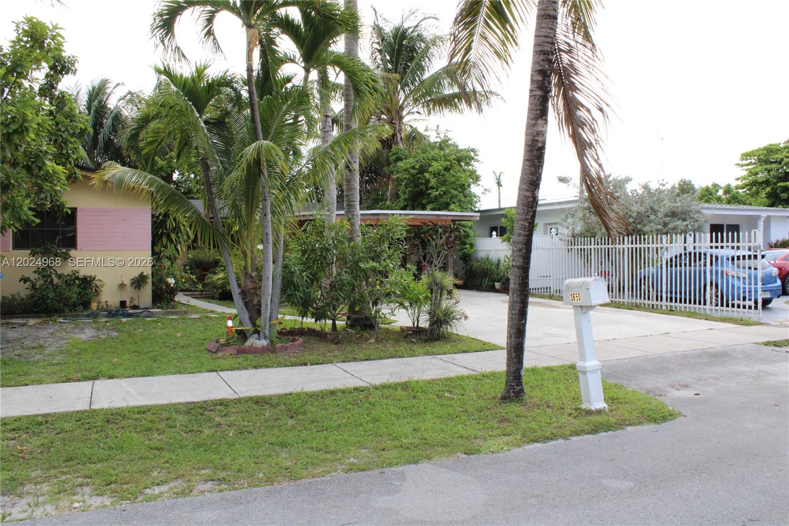 A residential property features a pink-accented house, a palm-filled front yard, and a white fence — 3650 SW 39th Ave, West Park FL 33023, WEST PARK, FL