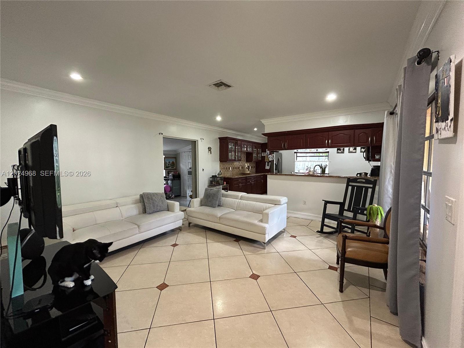 A living room features white sofas, tile flooring, and an open kitchen with dark cabinetry — 3650 SW 39th Ave, West Park FL 33023, WEST PARK, FL